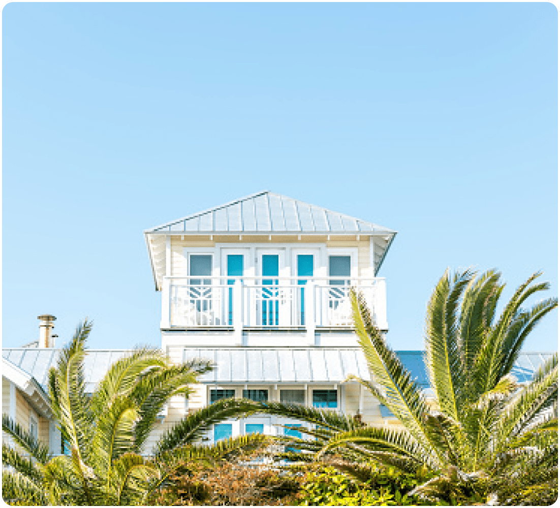 White beach house with palm tree.