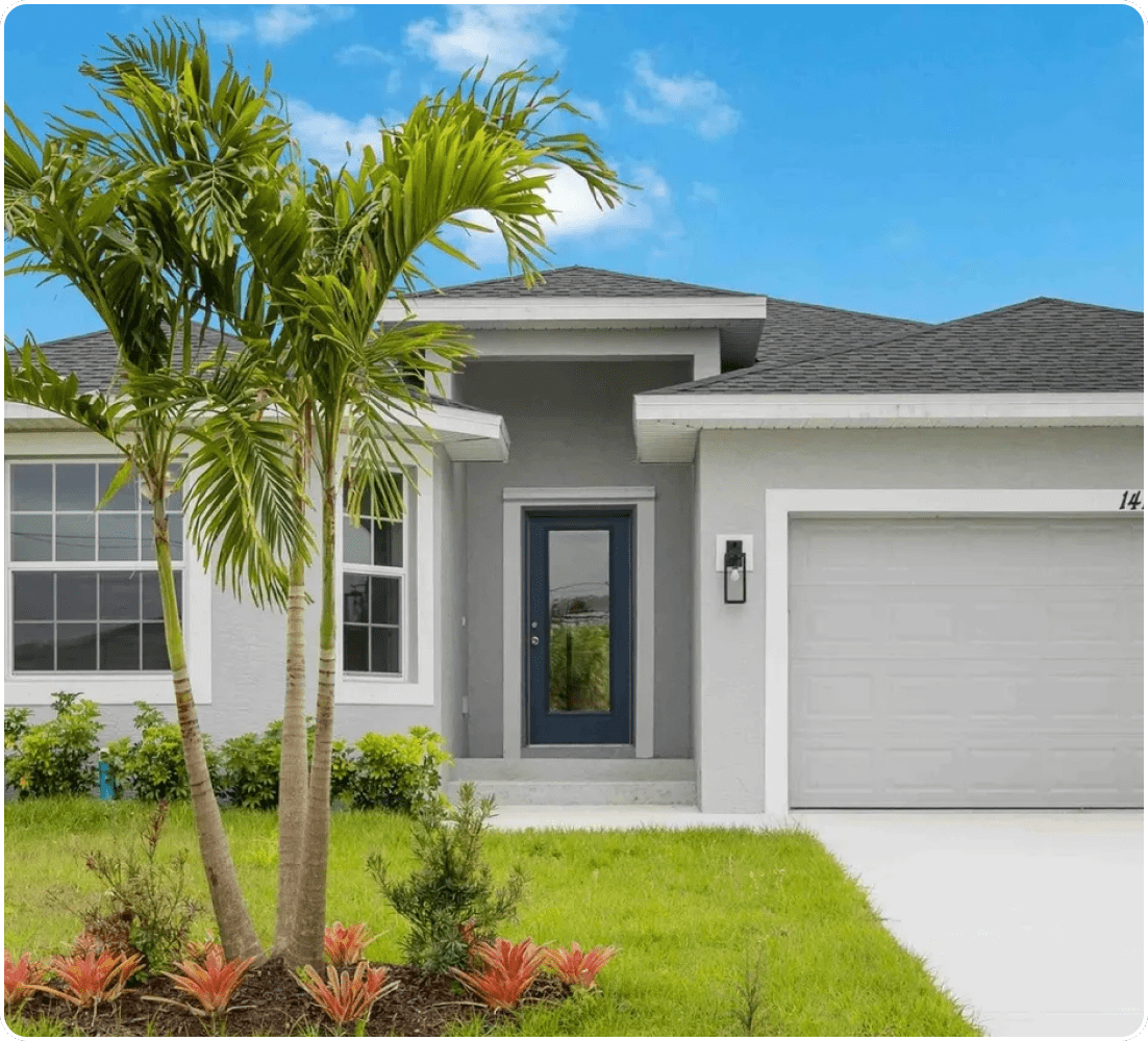 Gray house with palm trees and a garage.