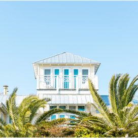 White beach house with palm tree.